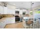 Kitchen features stainless appliances, granite countertops, travertine backsplash and white cabinets at 5608 Holmes Blvd, Holmes Beach, FL 34217