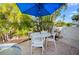 Outdoor patio table and chairs with landscaping and a blue umbrella at 5608 Holmes Blvd, Holmes Beach, FL 34217