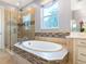 Close up of bathroom showing soaking tub with mosaic tile and a seamless glass shower at 5742 Hydrangea Cir, Sarasota, FL 34238