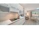 Well-appointed kitchen with white cabinetry, a stylish backsplash, and a cooktop overlooking a comfortable living area at 5856 Meriwether Pl, Sarasota, FL 34232