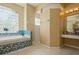 Bathroom with glass block window, shower, and a bathtub with blue mosaic tile surround at 622 147Th E St, Bradenton, FL 34212