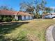 Charming single-story home with a red tile roof, lush lawn, and mature trees providing ample shade at 670 Venice Ln, Sarasota, FL 34242