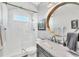 Updated bathroom with a glass-enclosed shower, marble vanity, and round mirror at 7257 Greystone St, Lakewood Ranch, FL 34202