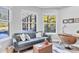 Bright living room with a gray sofa, wood accents, and natural light from large windows overlooking the pool at 7257 Greystone St, Lakewood Ranch, FL 34202
