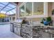 Outdoor kitchen with a built-in grill and stone accents, located near the screened-in pool at 7257 Greystone St, Lakewood Ranch, FL 34202