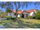 Stunning exterior view of home with tile roof, lush landscaping, and mature trees on a sprawling green lawn at 7261 Villa D Este Dr, Sarasota, FL 34238