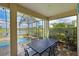Outdoor dining area under a screened-in patio, with a view of the pool and lake at 1017 Siberian Glen, Bradenton, FL 34212