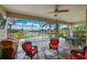 Inviting screened lanai features comfortable seating, a ceiling fan, and a beautiful view of the pool and lake at 1017 Siberian Glen, Bradenton, FL 34212