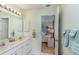 Bright bathroom featuring double sinks, white cabinetry, and a view into an adjacent bedroom at 1041 Capri Isles Blvd # 232, Venice, FL 34292