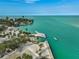 Scenic aerial view of a beach, palm trees, and a modern pier extending into turquoise waters at 105 Pass Key Rd # 105, Sarasota, FL 34242
