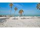 Tranquil beach scene with lounge chairs and tables facing the ocean under clear blue sky at 105 Pass Key Rd # 105, Sarasota, FL 34242