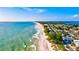 Sweeping aerial view showcases the coastline, beach, and nearby homes under a vibrant blue sky at 1123 Riverscape St # D, Bradenton, FL 34208