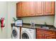 Well-organized laundry room featuring modern washer and dryer, granite countertops, and wooden cabinets at 1123 Riverscape St # D, Bradenton, FL 34208