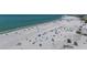 Aerial shot of a vibrant beach featuring white sand, turquoise water, and beach umbrellas at 1163 Coquille St # 207, Sarasota, FL 34242