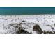 Drone's-eye view of a wide sandy beach with blue ocean, foliage, and beachgoers at 1163 Coquille St # 207, Sarasota, FL 34242