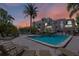 A community pool with lounge chairs and palm trees with a pink and orange sky in the distance at 1163 Coquille St # 207, Sarasota, FL 34242