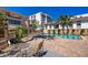 A community pool and jacuzzi surrounded by brick with seating and palm trees at 1163 Coquille St # 207, Sarasota, FL 34242