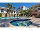 Community pool featuring a hot tub, lounge chairs, and palm trees with buildings in the distance at 1163 Coquille St # 207, Sarasota, FL 34242