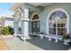 Close-up of the arched entryway with decorative glass doors, stone bench, and lush greenery at 12103 Shadow Run Blvd, Riverview, FL 33569