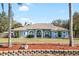 Charming light blue home featuring arched windows and mature landscaping against a clear blue sky at 12103 Shadow Run Blvd, Riverview, FL 33569