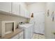 Bright laundry room featuring white cabinets, a countertop, and modern washer and dryer units at 12103 Shadow Run Blvd, Riverview, FL 33569