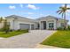 Stunning home featuring a three-car garage, manicured landscaping, and brick-paved driveway at 12557 Galapagos Ct, Venice, FL 34293