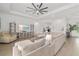 Large living room with sectional sofa, ceiling fan, and entertainment center with decor at 12557 Galapagos Ct, Venice, FL 34293