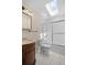 Bathroom with white tile, skylight, shower over tub and wood vanity at 1665 Harmony Dr, Port Charlotte, FL 33952