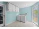 Laundry room with washer, dryer, storage cabinets and access to the outside with a bright blue wall at 1665 Harmony Dr, Port Charlotte, FL 33952