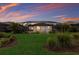 Beautiful backyard featuring a screened pool, lush lawn, and tasteful landscaping at dusk at 20892 Cattail Blvd, Venice, FL 34292