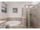 Bright bathroom showcasing a soaking tub and glass-enclosed shower with neutral tile at 20892 Cattail Blvd, Venice, FL 34292