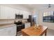 Well-lit kitchen with stainless steel appliances, granite countertops, and a wooden island at 20892 Cattail Blvd, Venice, FL 34292