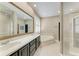 Elegant bathroom featuring dual sinks, a jacuzzi tub, and a seamless glass shower at 22235 Panther Loop, Bradenton, FL 34202