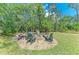 Outdoor firepit with chairs surrounded by mature trees and green grass at 22333 Panther Loop, Bradenton, FL 34202
