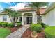 Welcoming front entrance with a tiled walkway, lush landscaping, and a charming doorway, framed by decorative columns at 22333 Panther Loop, Bradenton, FL 34202