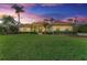 Inviting single-story home with a vibrant green lawn, mature trees, and well-manicured landscaping under a beautiful sunset sky at 22333 Panther Loop, Bradenton, FL 34202