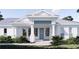 Inviting front entry showcases a blue door, white columns, and a charming brick walkway surrounded by lush greenery at 2508 Belvoir Blvd, Sarasota, FL 34237