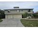 Two-story home featuring a light green exterior, multiple garage doors, and professionally landscaped yard at 33 Tee View Pl, Rotonda West, FL 33947