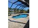 Outdoor pool with brick patio, surrounded by palm trees under a screened enclosure at 33 Tee View Pl, Rotonda West, FL 33947