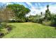 Spacious backyard features a lush lawn, mature trees, and manicured landscaping, perfect for outdoor activities and relaxation at 4444 Highland Oaks Cir, Sarasota, FL 34235