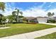 Single-story home featuring a lush green lawn, palm trees, and a well-maintained landscape at 4444 Highland Oaks Cir, Sarasota, FL 34235