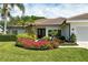 Well-maintained home exterior featuring colorful flower beds and lush tropical landscaping at 4444 Highland Oaks Cir, Sarasota, FL 34235