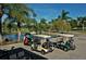 A row of golf carts are parked next to palm trees, perfect for enjoying a day on the golf course at 4444 Highland Oaks Cir, Sarasota, FL 34235