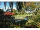 View of the golf course and pond, a red awning for shade and lush landscaping at 4444 Highland Oaks Cir, Sarasota, FL 34235