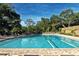 Community pool with lane dividers, lounge chairs, mature trees and a brick tile deck at 4444 Highland Oaks Cir, Sarasota, FL 34235