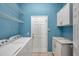 Bright laundry room with blue walls, tile floors, wire shelves and white cabinets at 4527 Barracuda Dr, Bradenton, FL 34208