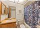 Cozy bathroom with a bath tub, flower-patterned curtain, wood cabinets and a wall mirror at 5729 Avista Dr, Sarasota, FL 34243