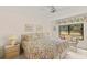 Cozy bedroom with bright floral bedding, a ceiling fan, and an airy window view of the lovely backyard at 5729 Avista Dr, Sarasota, FL 34243