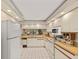 Well-lit kitchen featuring white cabinets, tiled floors, and updated appliances at 5729 Avista Dr, Sarasota, FL 34243