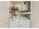 Functional laundry room includes a washer, dryer, shelving, and storage space behind louvered doors at 5729 Avista Dr, Sarasota, FL 34243